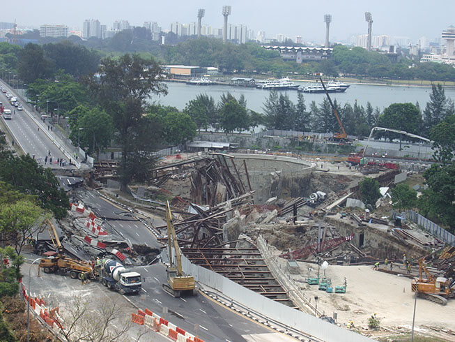 Construction vehicles surrounding a collapsed road surface.