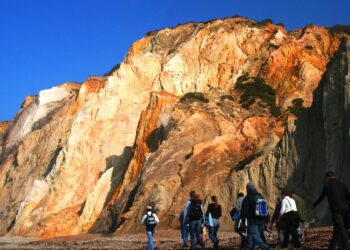 Researchers hiking in front of a dramatic rocky cliffside